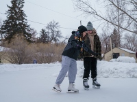 Two people enjoying a leisurely skate on an outdoor rink. Two people enjoying a leisurely skate on an outdoor rink.